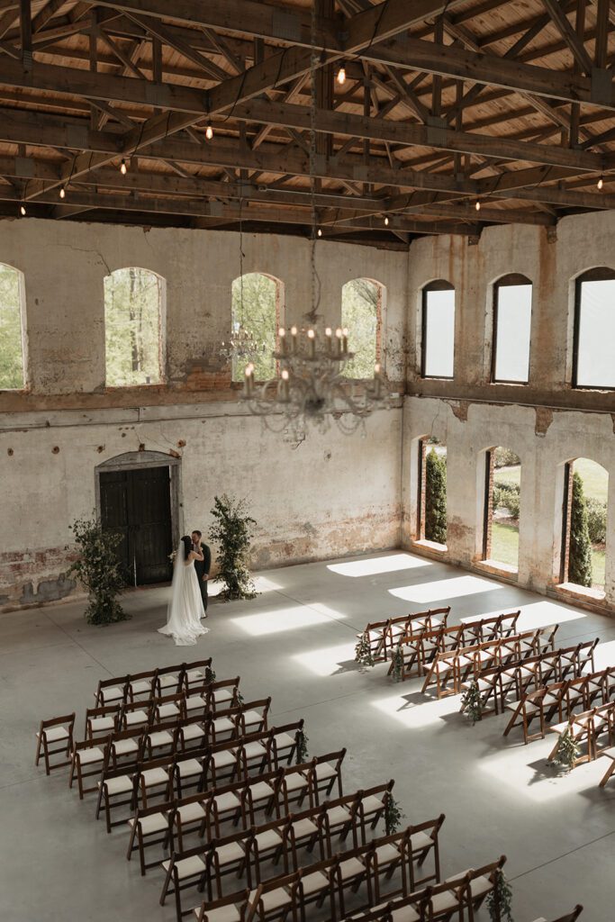 bride-in-sleek-satin-dress-and-groom-in-an-emerald-suit-at-the-historic-providence-cotton-mill