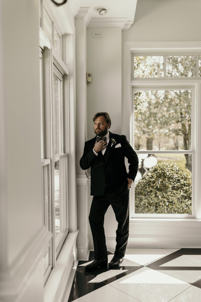 Groom portraits near the window with black and white checkered floor.