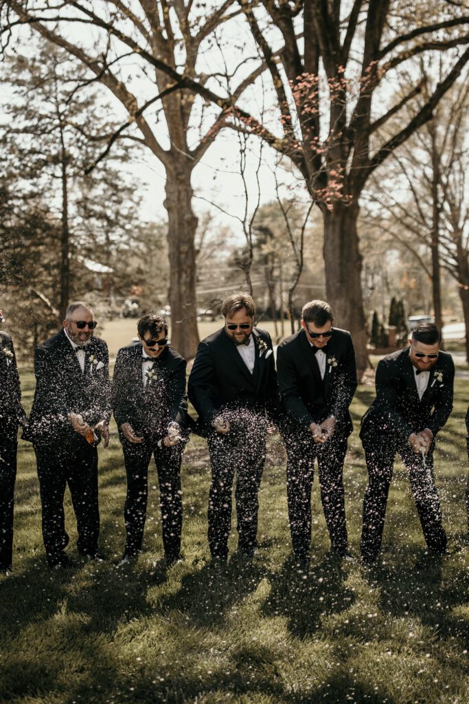 Groom and groomsmen candid photo of spraying beer with sunglasses on.