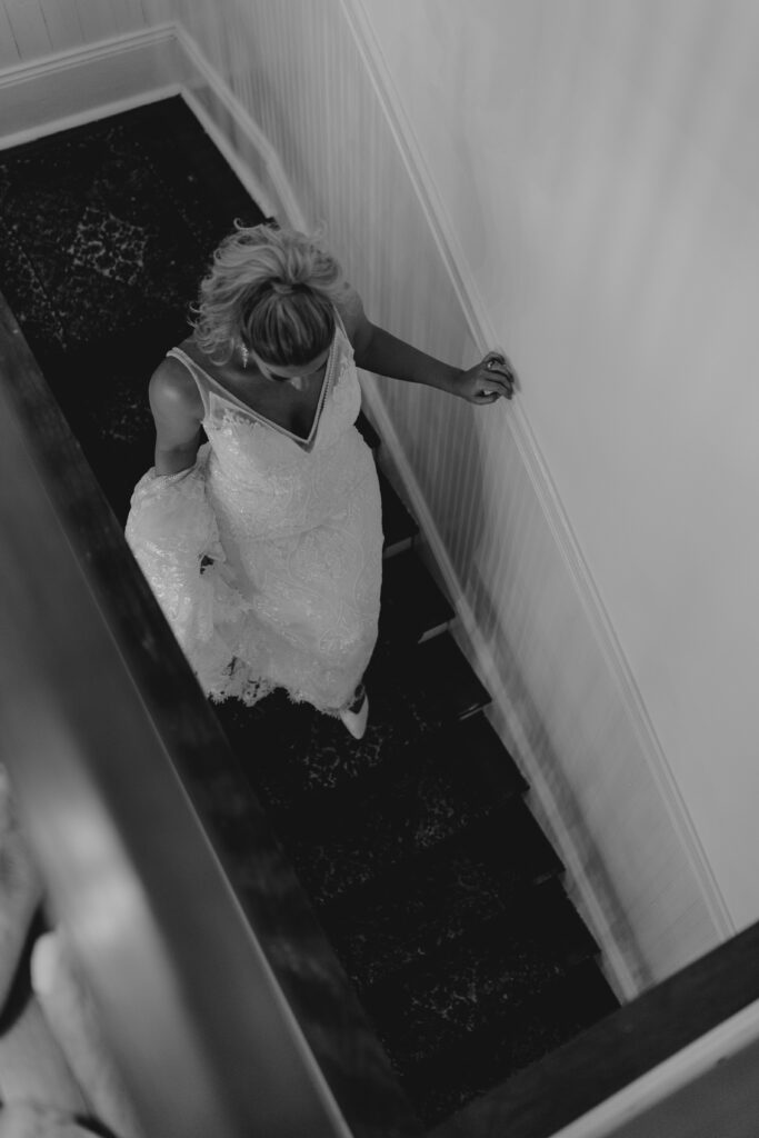 Bride walking down stairs of wedding venue to join ceremony.