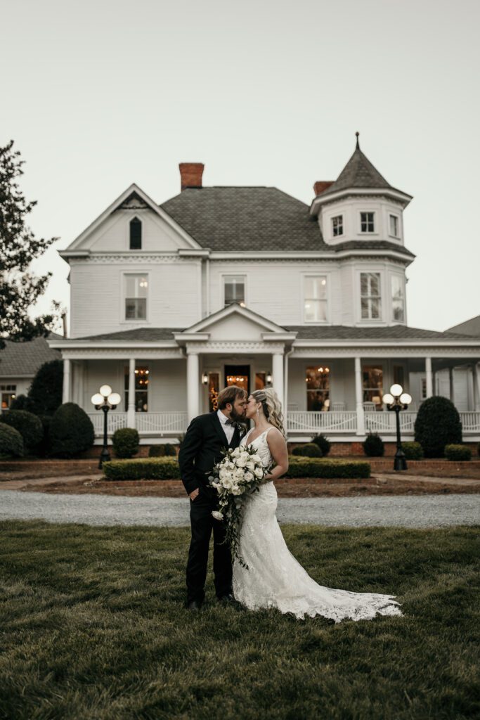 bride and groom kissing in front of The Grande Victorian wedding venue