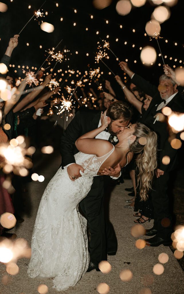 bride and groom dip kiss during a direct flash sparkler exit
