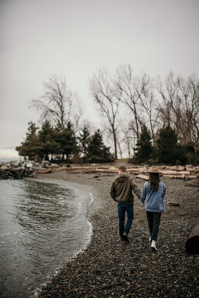 The secret beach of Olympic Sculpture park with a couple walking along the shore for their engagement session