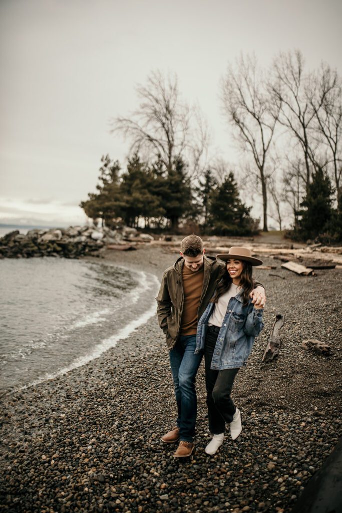 The secret beach of Olympic Sculpture park with an engaged couple strolling across the shore 