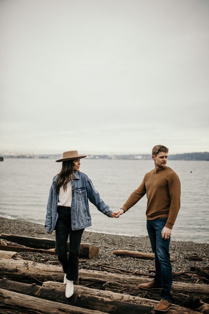couple holding hands at their couples session with the olympic mountains visible in the background