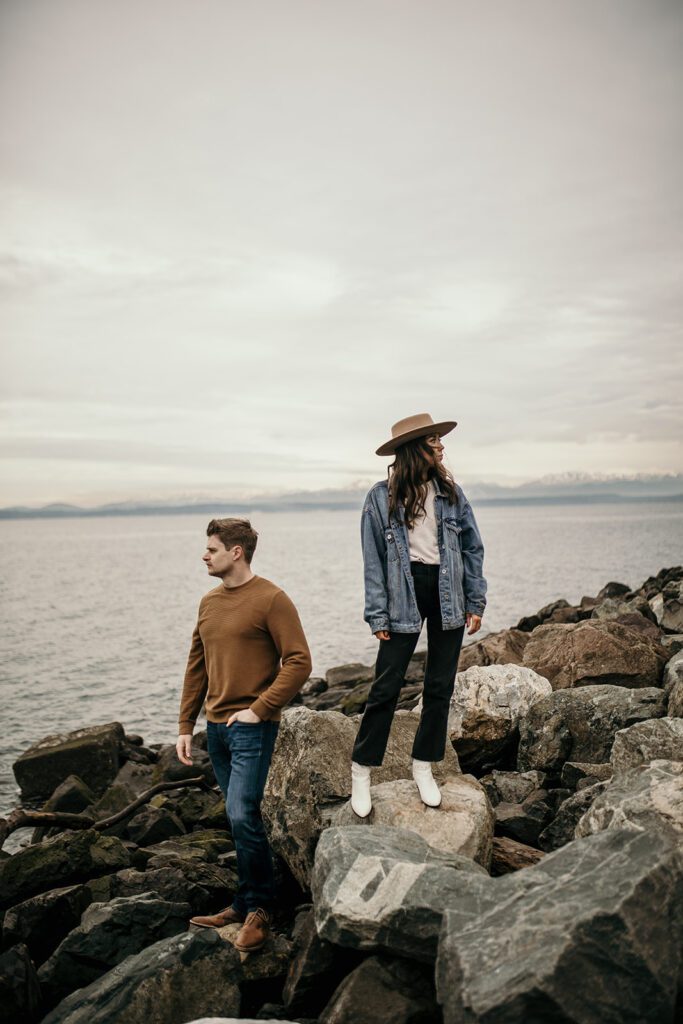 portrait of couple standing on alike beach with the olympic mountains in the background
