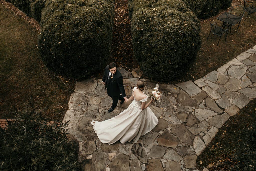 classic wedding couple walking along path at their mansion venue