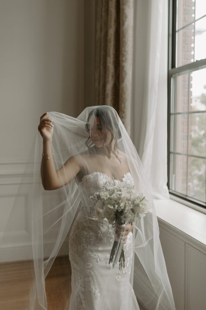 bride-underneath-veil-by-large-window