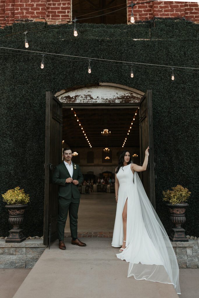 greenery-wall-with-string-lights-over-exposed-brick-during-cocktail-hour-at-wedding-venue