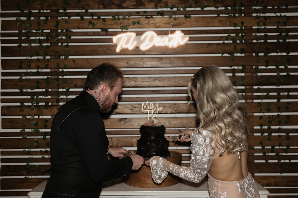 cake-cutting-with-black-vintage-inspired-wedding-cake-with-till-death-do-us-part-neon-sign