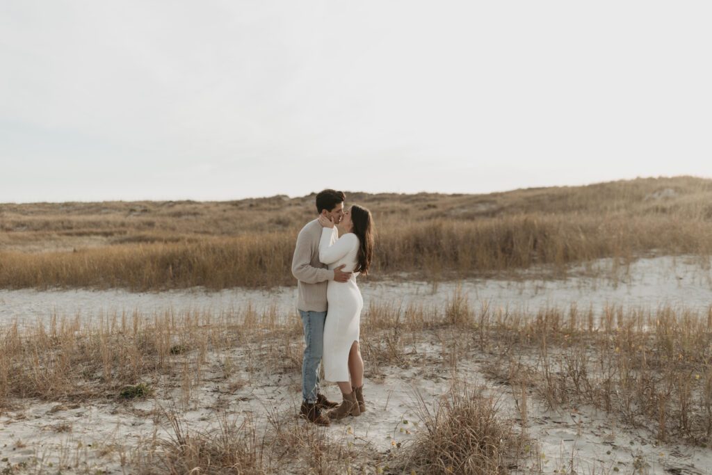 neutral engagement session with white knit dress on the sand dunes of Wrightsville beach, North Carolina