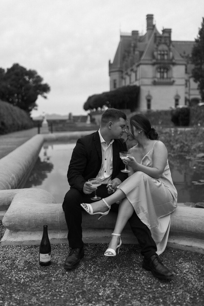 couple sharing champagne in the italian garden at the biltmore estate for their engagement session