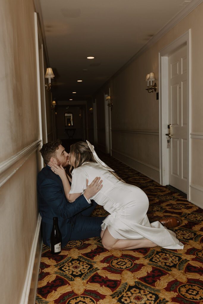 bride and groom kissing in hotel hallway